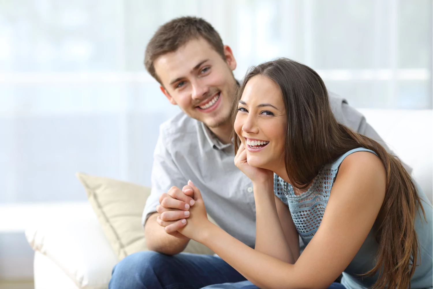 Smiling wife holding hands with her husband while sitting together, showing support for husband’s calling