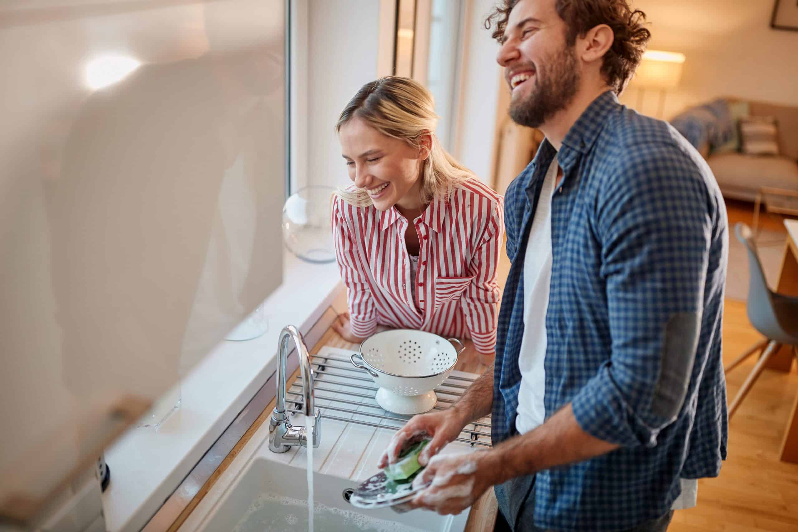 Lovely couple doing the dishes together in the kitchen.