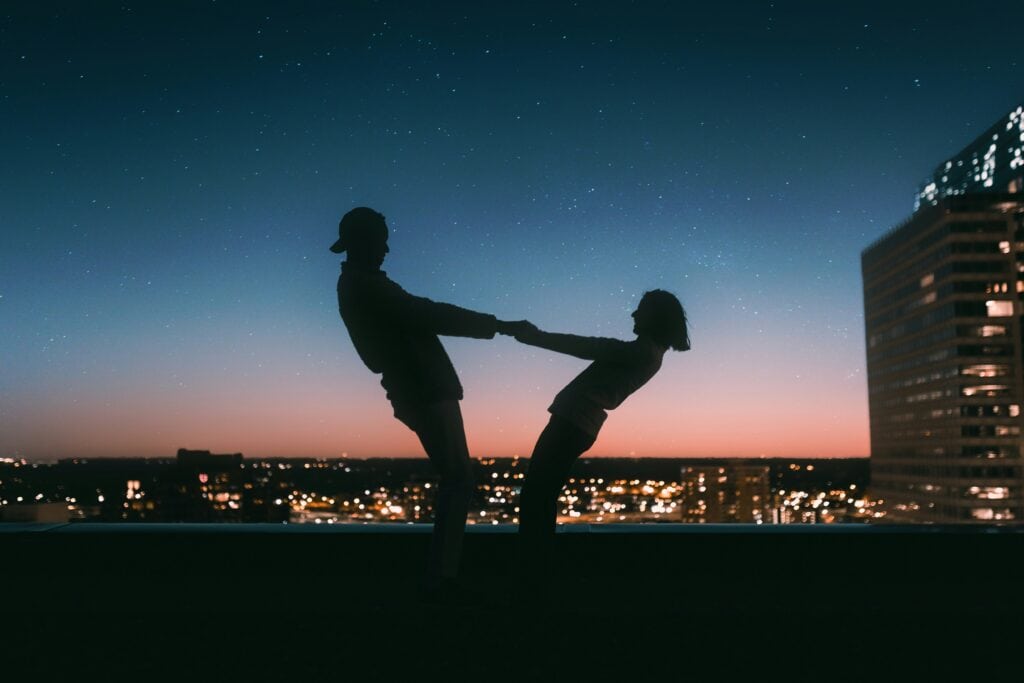 This image shows a couple dancing in front of a skyline. They are in the form of a silhouette while the sky reflects a cascade of colors. (What does the Bible say about dating?)