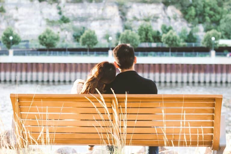 This image shows a couple on a park bench, looking out towards the mountains.