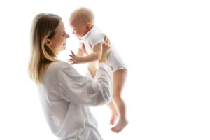 Mother holding and smiling at her baby, representing how we define nurture through love, presence, and care.