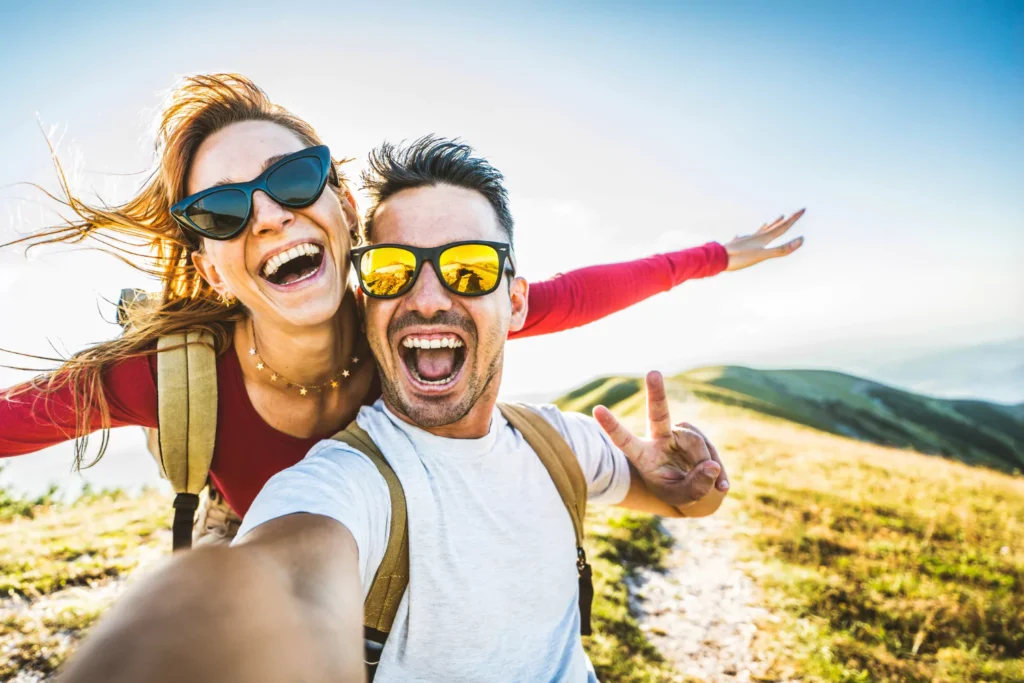 Happy couple hiking on a mountain trail, smiling and celebrating together — symbolizing overcoming stress in marriage and building a stronger relationship.