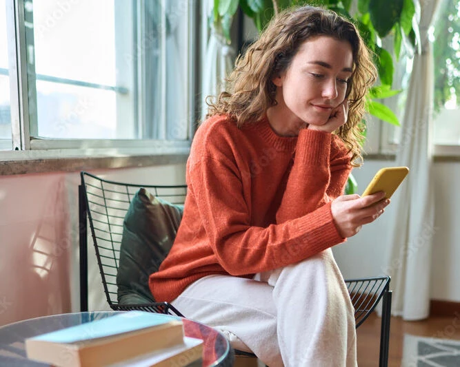 Young woman sitting on a chair looking at her phone