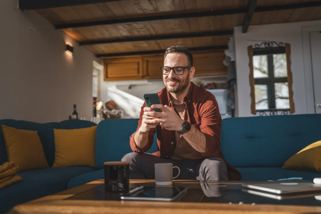 Smiling man sitting on a couch looking at his phone