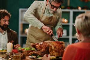 How to stay thankful when the holiday falls apart. Senior man carving thanksgiving turkey for family dinner