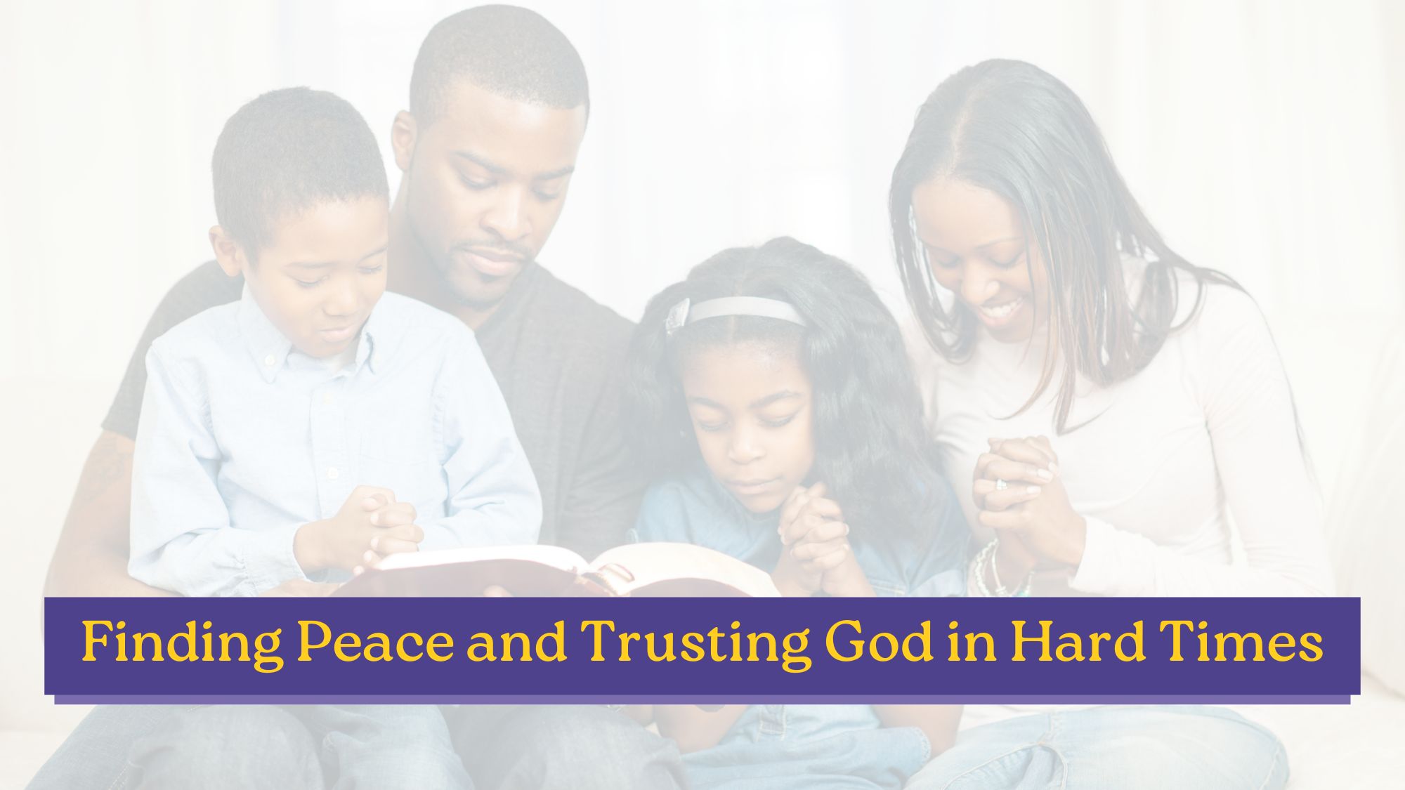 A family of four with heads bowed in prayer together over an open Bible, illustrating finding peace and trusting God in hard times.