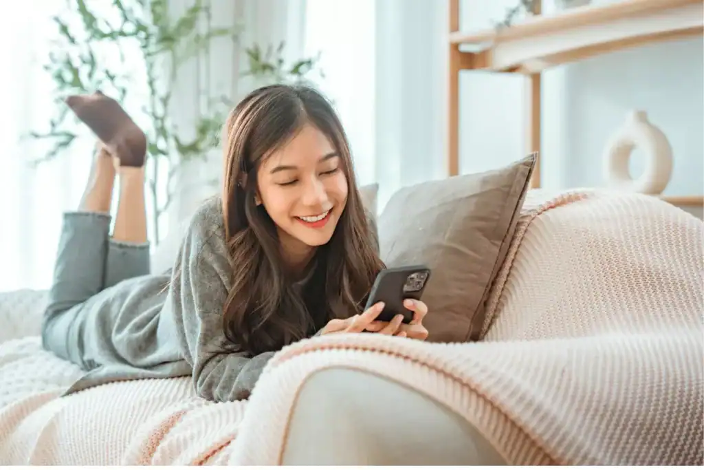Teen lying on a couch using a smartphone at home, raising the question, “When should I let my child start dating?”