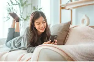 Teen lying on a couch using a smartphone at home, raising the question, “When should I let my child start dating?”