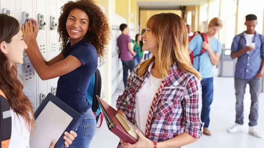 Three smiling high school girls at their lockers