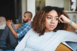 Unhappy couple and sad woman upset after argument or conflict with her man on home sofa and needs a marriage first aid kit to help with disagreements.