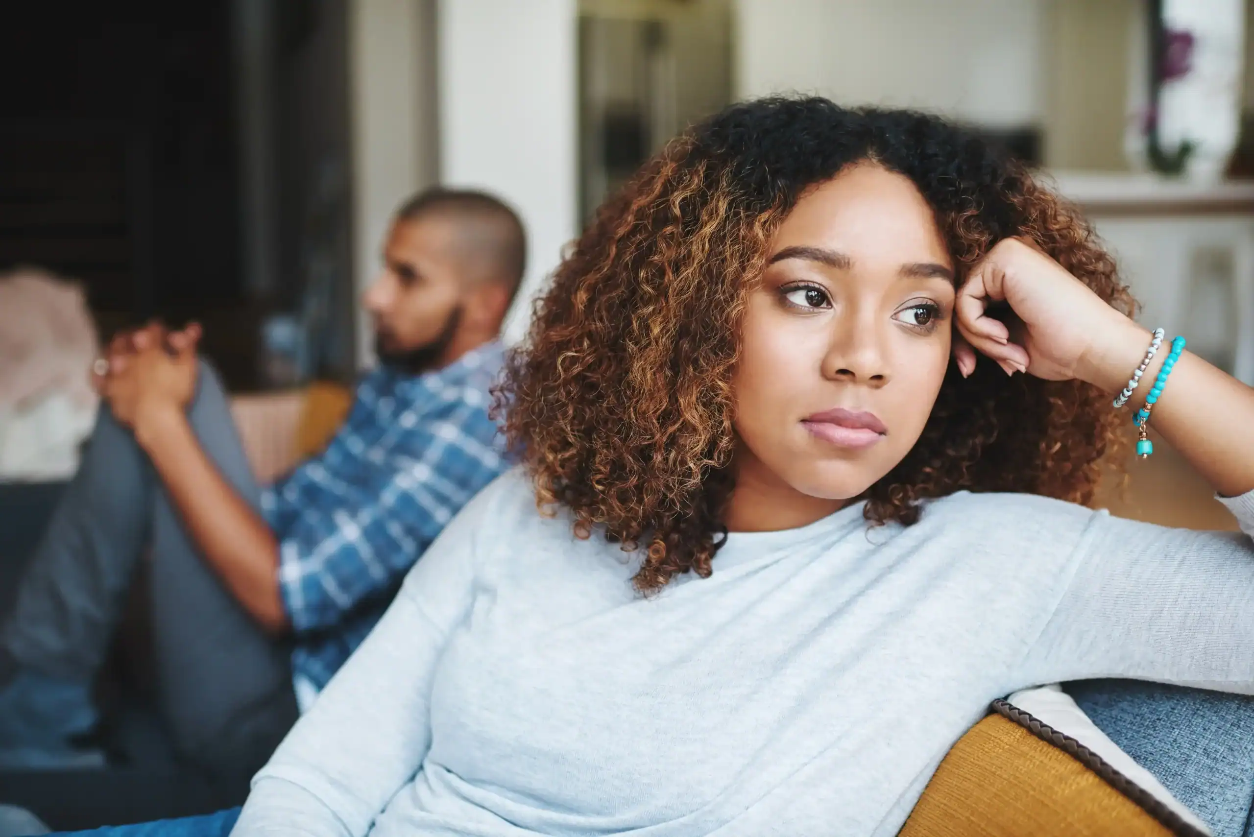 Unhappy couple and sad woman upset after argument or conflict with her man on home sofa and needs a marriage first aid kit to help with disagreements.