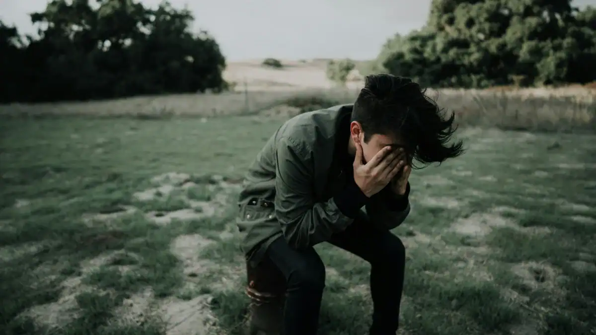 A distraught young man sitting alone in a field