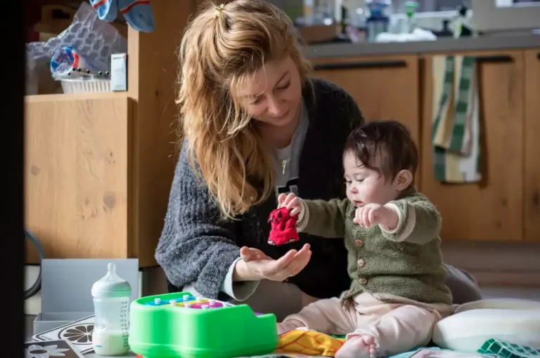 Caregiver sitting closely with a young child on a sofa in a home environment, demonstrating family support and connection during early childhood intervention and early intervention services.
