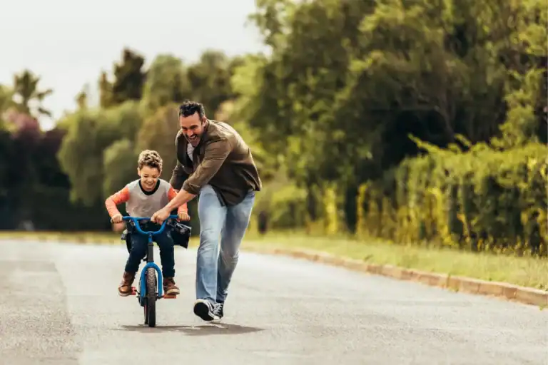Father helping his young child ride a bike, illustrating biblically based fatherhood through presence and encouragement.