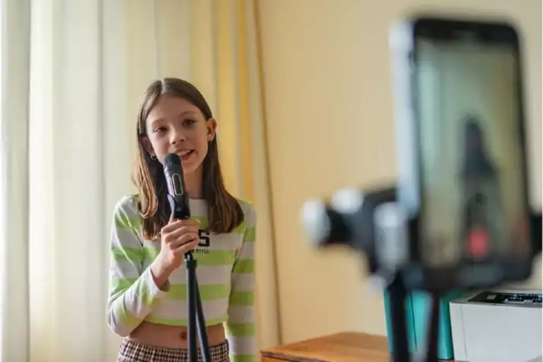 Young girl with a microphone in front of her camera phone trying to become a social media influencer.