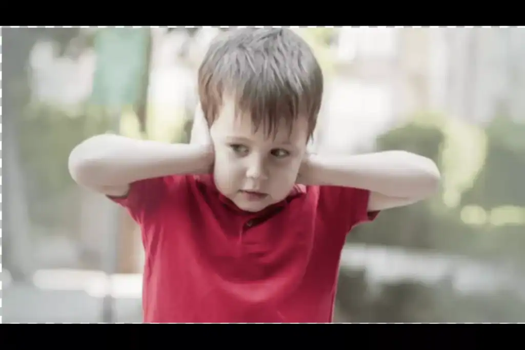 Young boy covering his ears in distress, illustrating a common sensory sensitivity linked to autism spectrum disorder.