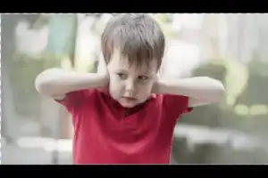 Young boy covering his ears in distress, illustrating a common sensory sensitivity linked to autism spectrum disorder.