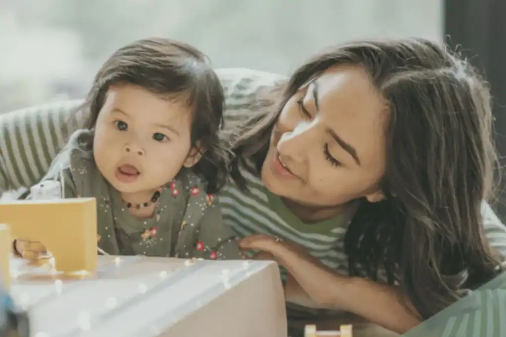 Mother closely watching toddler play with wooden toy, illustrating early signs of autism in toddlers.