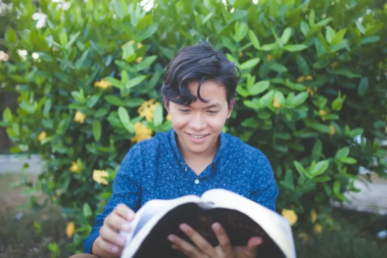 Young man smiling while reading outdoors, reflecting on how to think biblically.