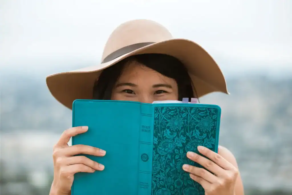 Teenage girl in a sunhat holding an open Bible, symbolizing a foundation in biblical truth.