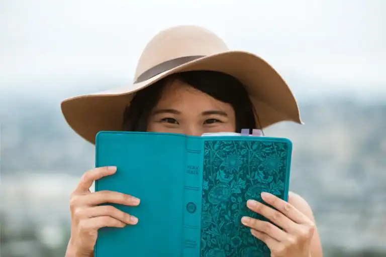 Teenage girl in a sunhat holding an open Bible, symbolizing a foundation in biblical truth.