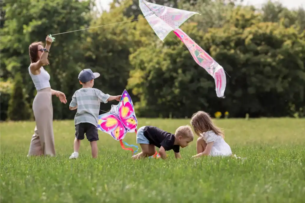 Children playing together in a grassy field, flying colorful kites and enjoying simple outdoor activities that reflect healthy family rhythms and connection.