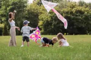 Children playing together in a grassy field, flying colorful kites and enjoying simple outdoor activities that reflect healthy family rhythms and connection.