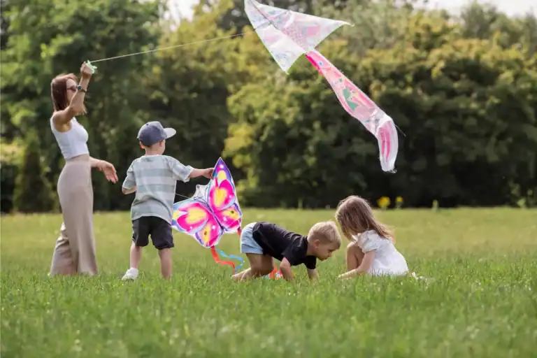 Children playing together in a grassy field, flying colorful kites and enjoying simple outdoor activities that reflect healthy family rhythms and connection.