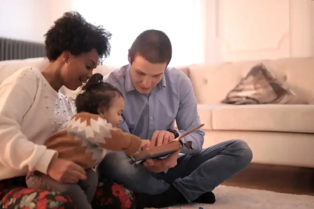 Parents sitting on the floor reading a Bible with their toddler, illustrating how to disciple a young child through everyday moments together.