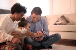 Parents sitting on the floor reading a Bible with their toddler, illustrating how to disciple a young child through everyday moments together.