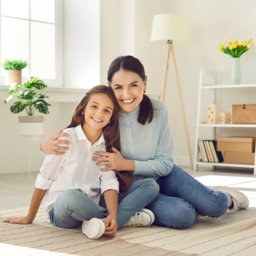 Smiling mother & young daughter sitting on the floor